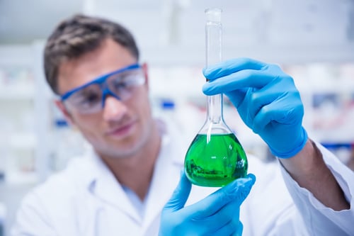 Chemist holding up beaker of green chemical in the laboratory-1