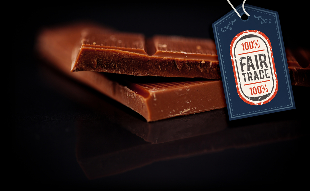 Fair Trade graphic against two blurred bar of dark chocolate